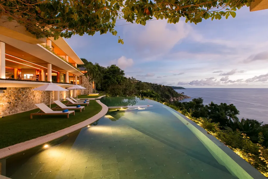 Infinity pool at dusk with the villa lit behind