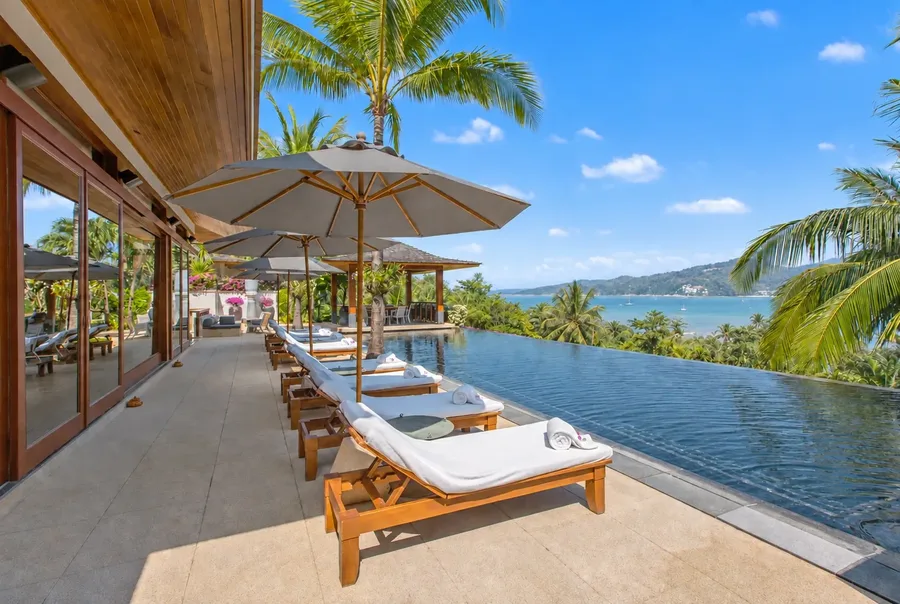 Sun loungers and umbrellas along the infinity pool, looking over Kamala Bay